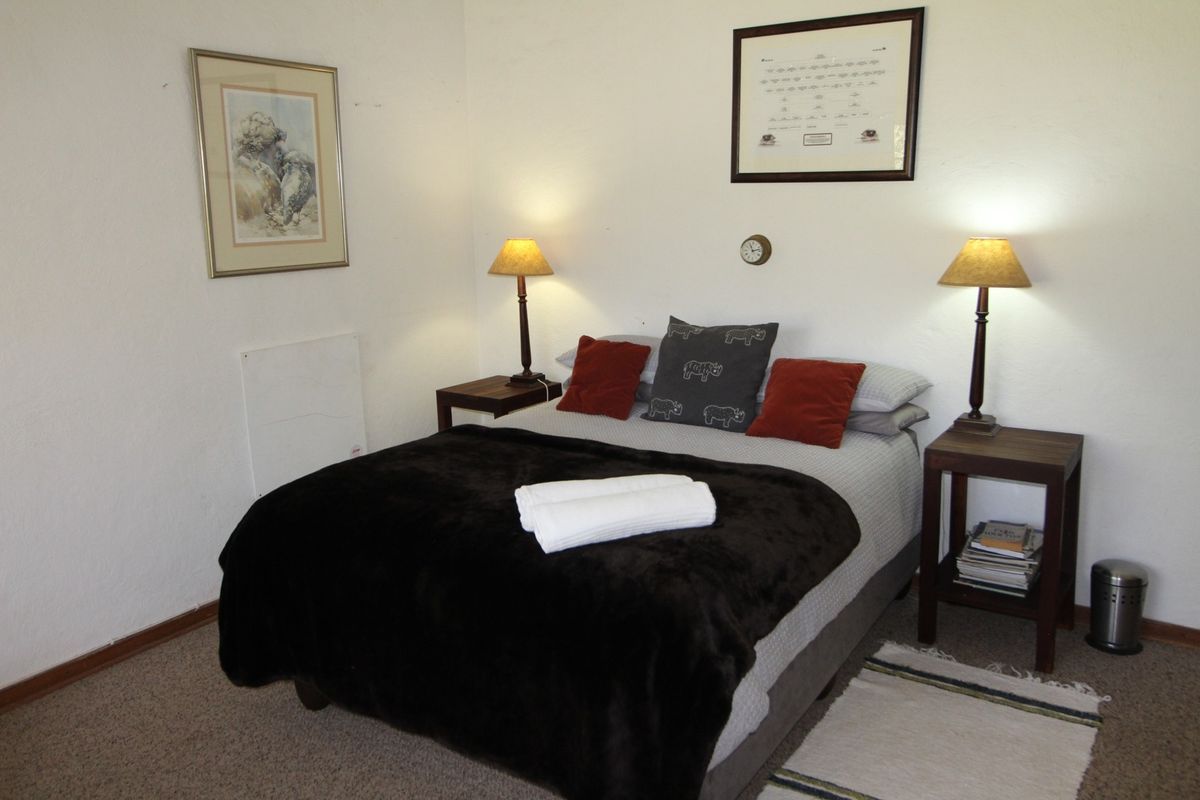 A cozy bedroom featuring carpeted flooring and a wall-mounted heater, providing a comfortable and functional sleeping space.