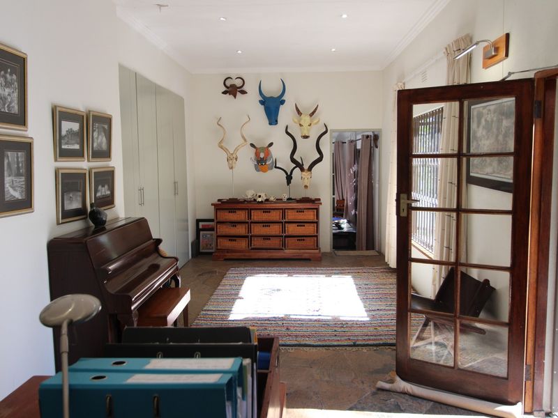 A well-lit living area featuring stone flooring, built-in storage cupboards, and a classic timber-framed glass door leading to an adjacent space.