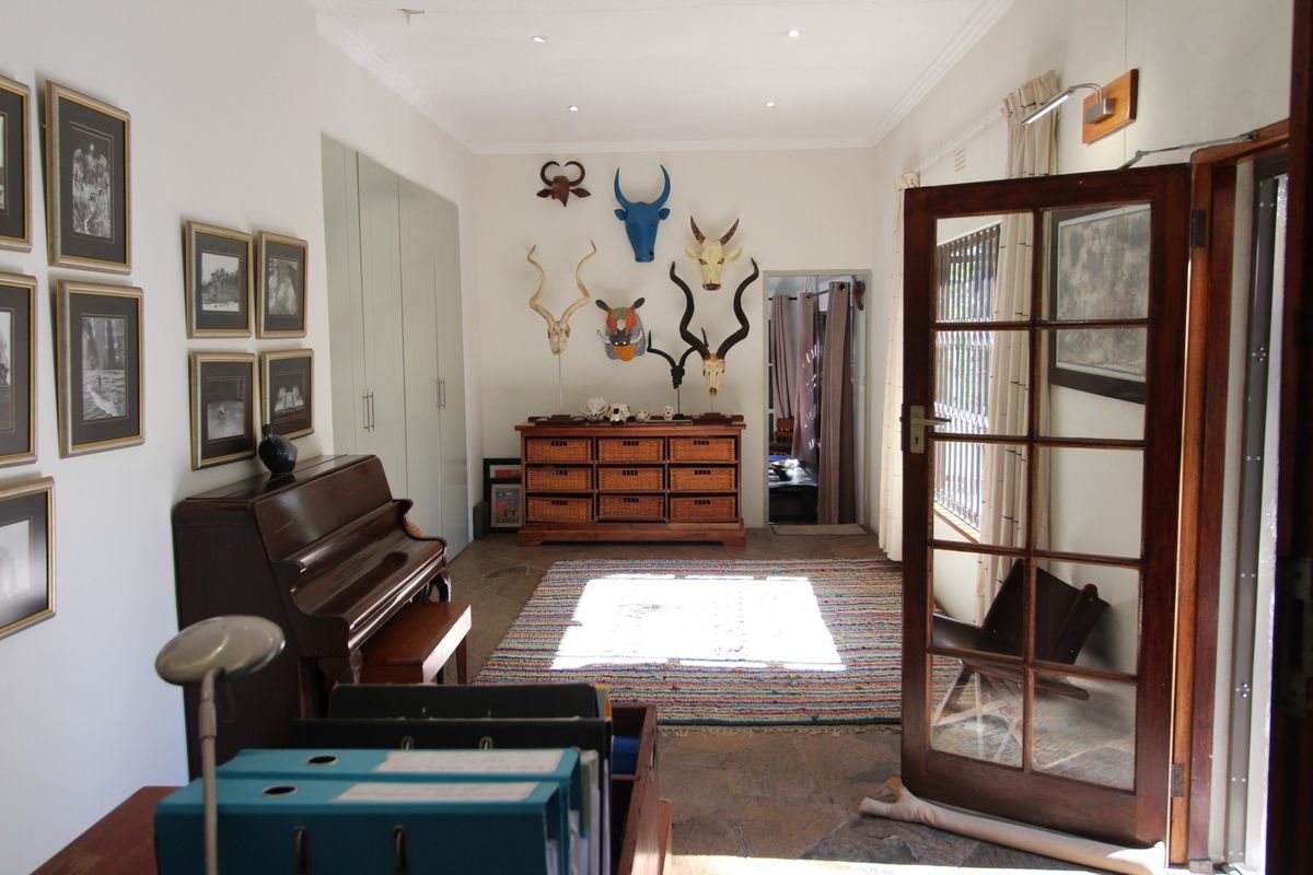 A well-lit living area featuring stone flooring, built-in storage cupboards, and a classic timber-framed glass door leading to an adjacent space.