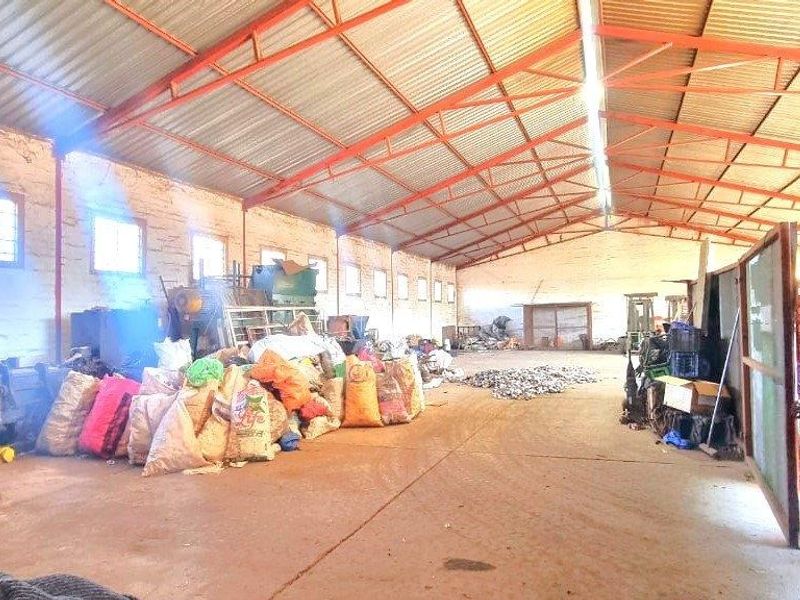 Spacious industrial warehouse or utility space featuring exposed steel roof trusses, concrete flooring, and brick masonry walls, suitable for storage or workshop use.