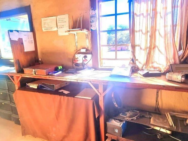 A functional industrial office space featuring a built-in desk, grid-pattern windows, and basic electrical infrastructure, suitable for administrative or site management tasks.