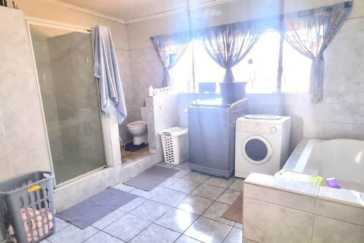 A functional bathroom featuring a shower enclosure, built-in bathtub, and toilet, with tiled walls and flooring throughout.