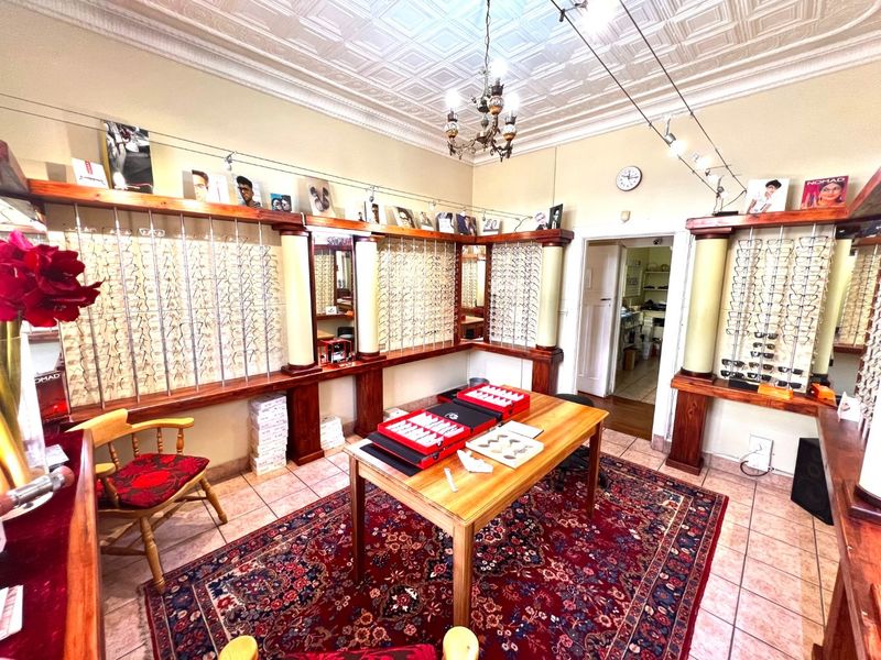 A well-maintained retail optical space featuring custom wooden display shelving, decorative ceiling detailing, and integrated track lighting.