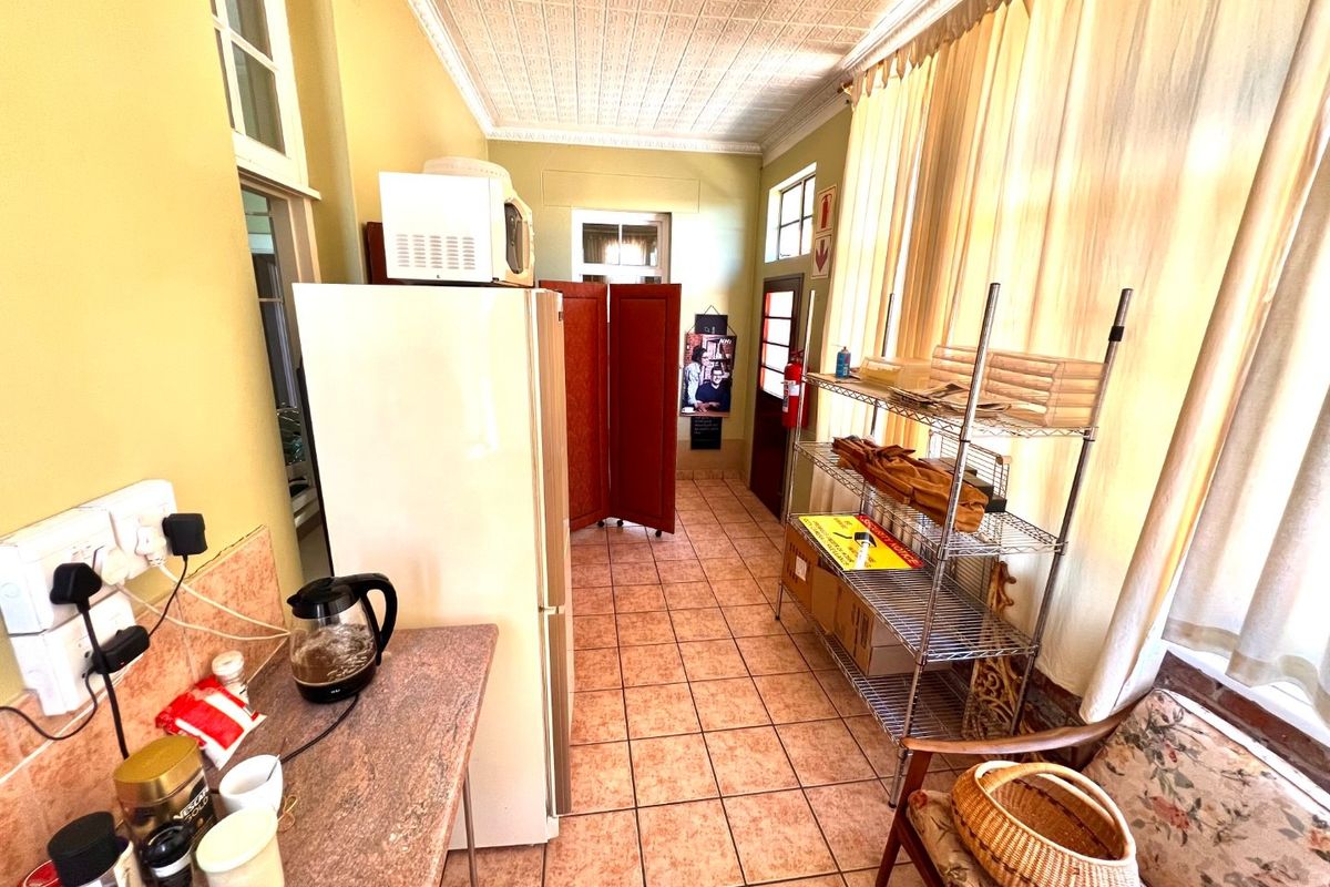 A functional kitchen area featuring tiled flooring, a classic pressed metal ceiling, and a granite countertop workspace.