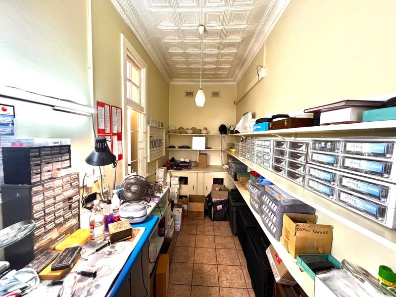 A functional utility or storage room featuring tiled flooring, pressed metal ceilings, and extensive built-in shelving and cabinetry for organized storage.