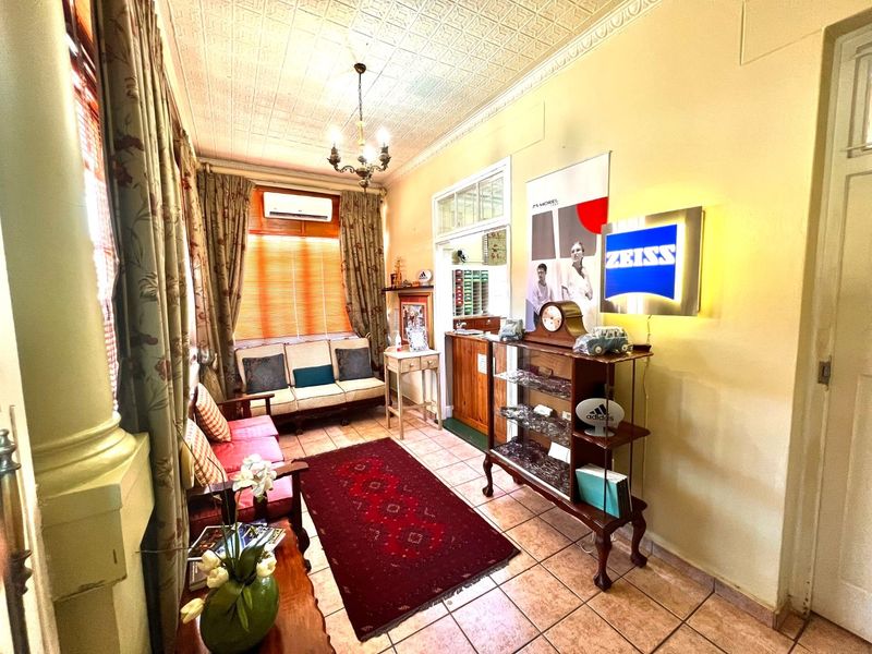 A waiting area or reception room featuring a decorative pressed metal ceiling, tiled flooring, and a wall-mounted split system air conditioner.
