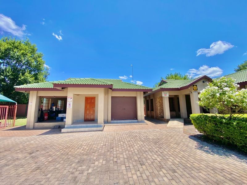 Front view of a commercial property featuring a paved driveway, tiled roof, and a combination of roller shutter and standard door access.