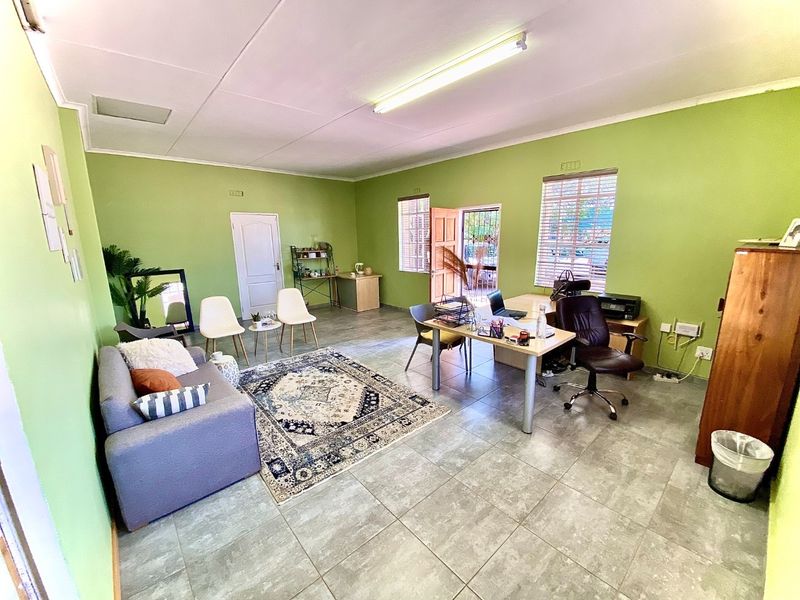 A functional office space featuring tiled flooring, fluorescent lighting, and natural light through venetian blinds, suitable for a professional business environment.