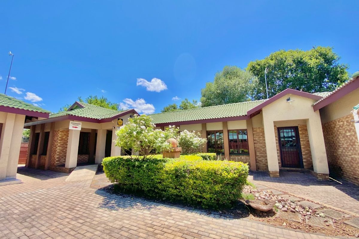 Front exterior view of a business property featuring brick paving, a landscaped garden, and a tiled roof structure.