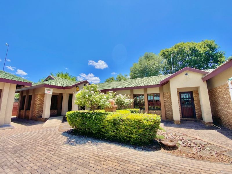Front exterior view of a business property featuring brick paving, a landscaped garden, and a tiled roof structure.