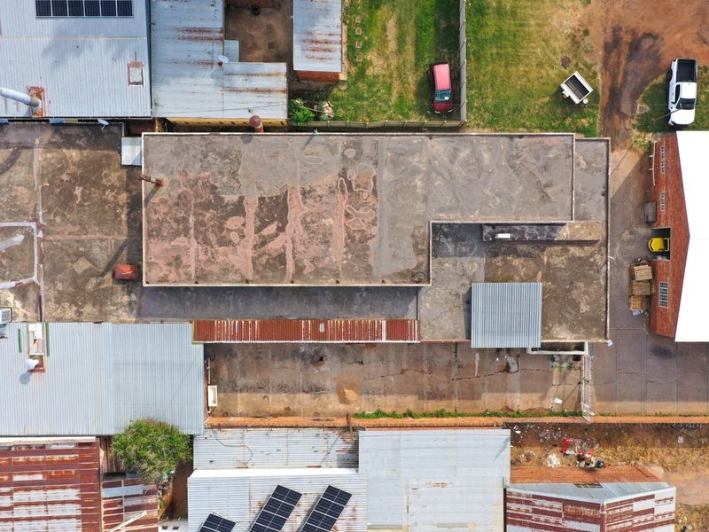 Aerial view of a commercial property complex featuring multiple buildings with corrugated metal and concrete roofing, solar panels, and paved yard space.