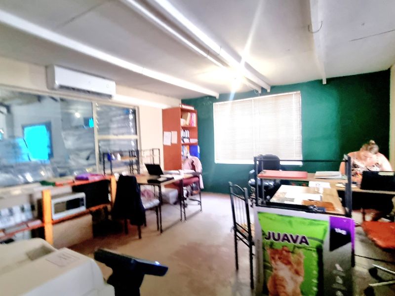 A functional commercial office space featuring an air conditioning unit, venetian blinds, and overhead fluorescent lighting, suitable for a professional work environment.