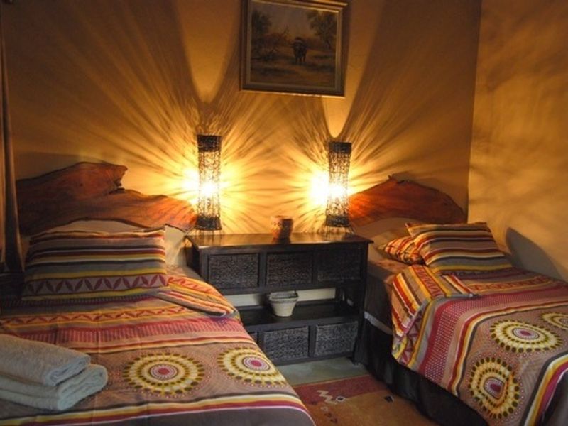 A cozy bedroom featuring twin beds with rustic wooden headboards and warm ambient lighting.
