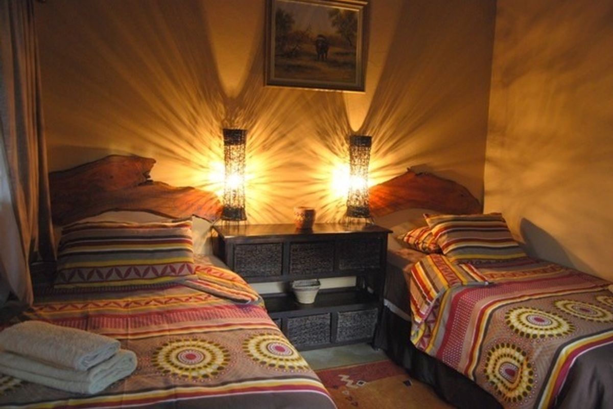 A cozy bedroom featuring twin beds with rustic wooden headboards and warm ambient lighting.