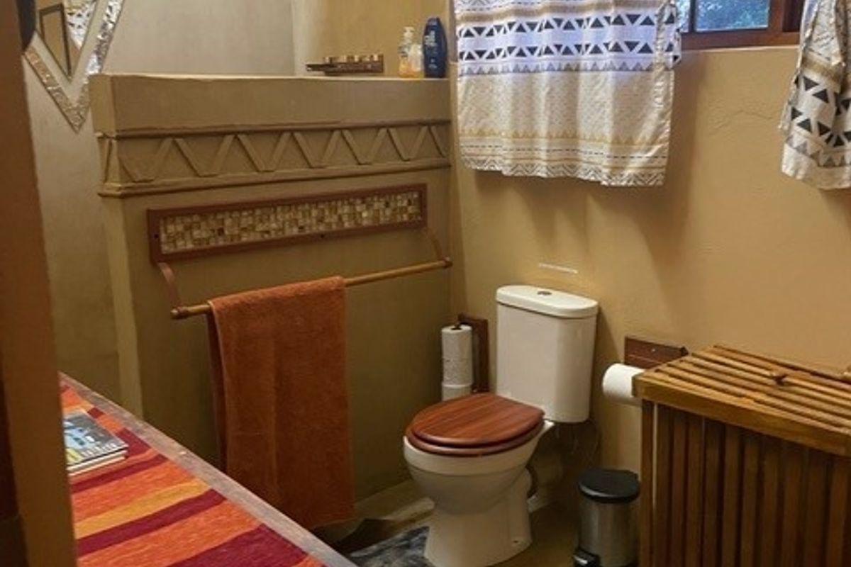 A rustic-style bathroom featuring a walk-in shower, toilet, and decorative tiled wall accents with warm earth-toned finishes.