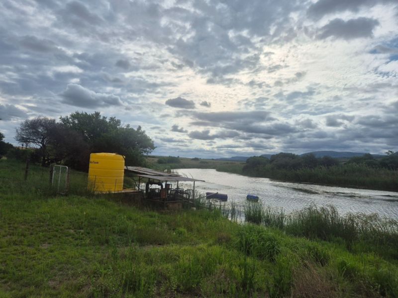 A scenic view of the farm riverfront featuring a water storage tank and pump infrastructure set against a natural landscape.