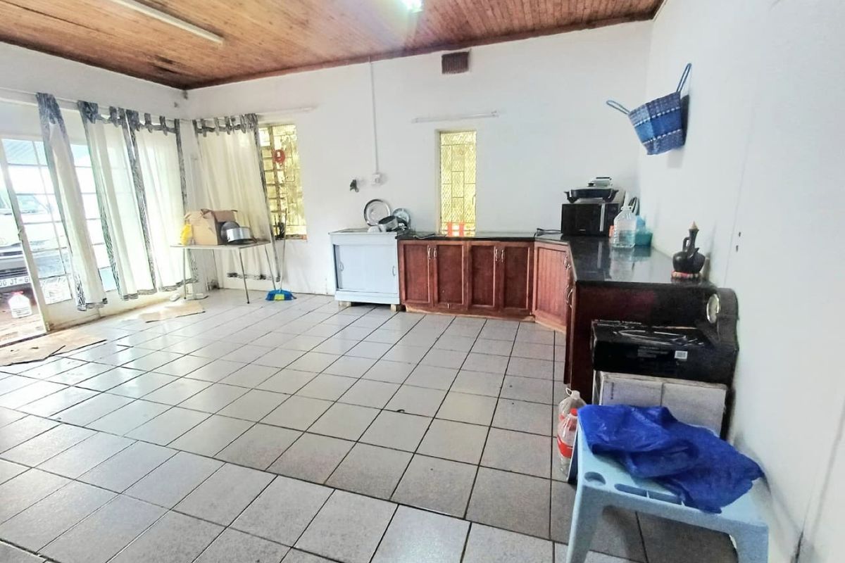 A functional kitchen area featuring tiled flooring, wooden ceiling, and built-in cabinetry with granite countertops, offering potential for modernization.