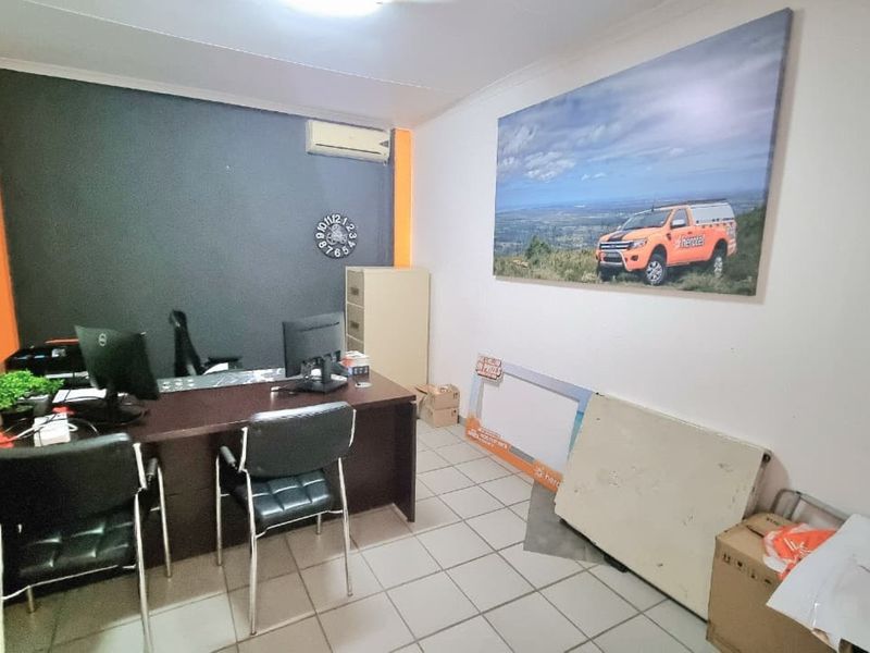 A functional commercial office space featuring tiled flooring and a wall-mounted split-system air conditioning unit.