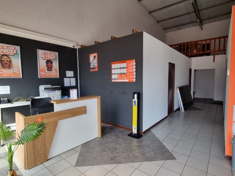 Commercial entry area featuring a reception desk, tiled flooring, and an open-plan layout with access to a mezzanine level.