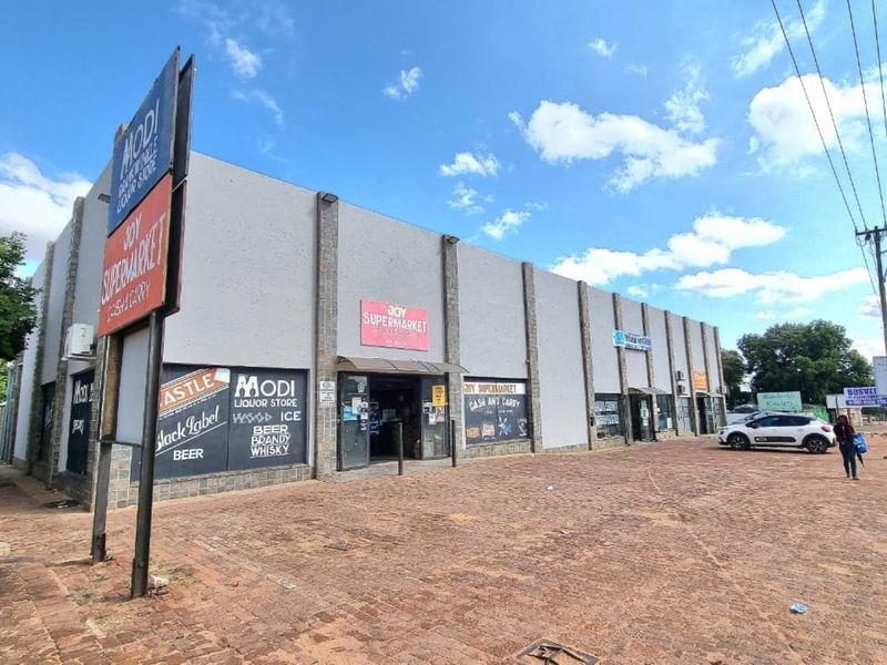 Commercial retail building featuring prominent signage, multiple storefront entrances, and an expansive paved parking area along the street frontage.