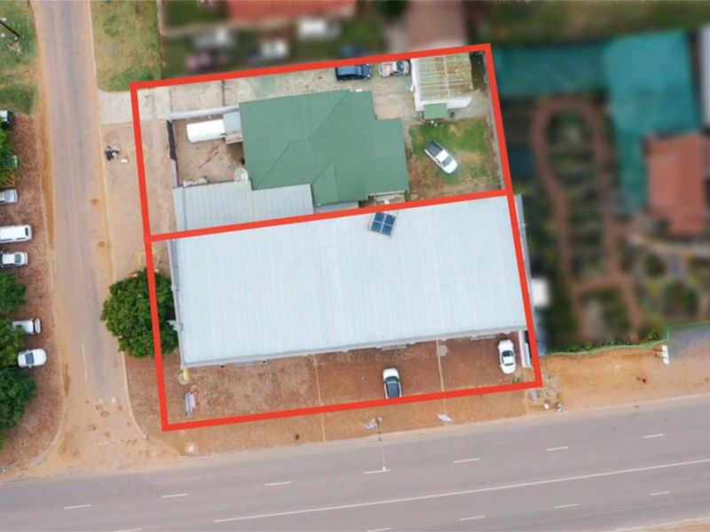 Aerial view of the commercial property showing the building layout, roof structure, and paved parking area with street access.