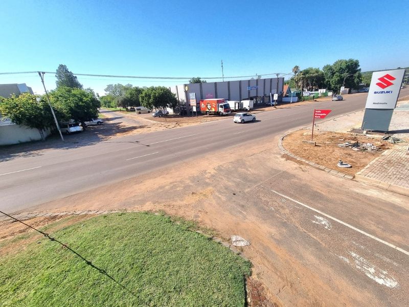 Elevated view of a commercial street intersection featuring paved roads, sidewalks, and prominent commercial signage.