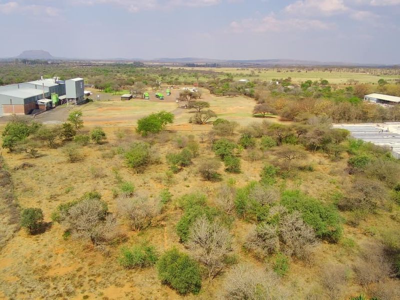 Aerial view of a large commercial vacant land plot featuring existing industrial infrastructure, silos, and warehouse facilities in a rural setting.
