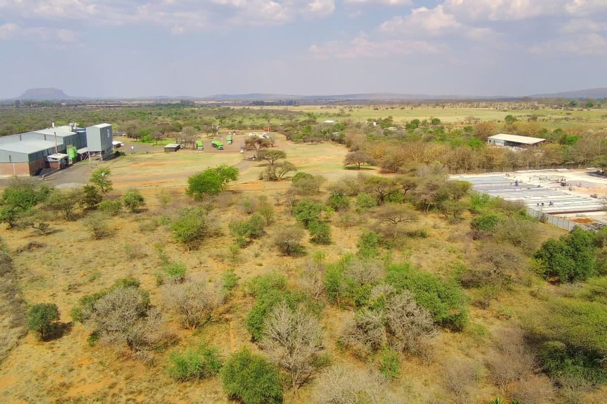 Aerial view of a large commercial property featuring industrial warehouse structures, silo infrastructure, and expansive undeveloped land.