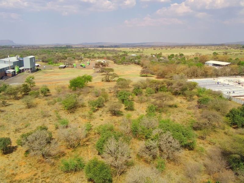 Aerial view of a large commercial property featuring industrial warehouse structures, silo infrastructure, and expansive undeveloped land.