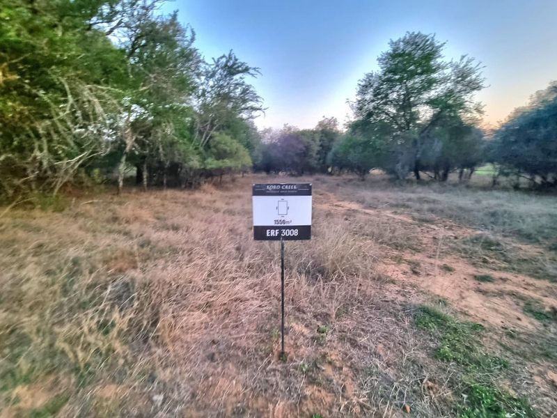 A vacant residential plot of land measuring 1550 square meters, featuring natural vegetation and established trees.