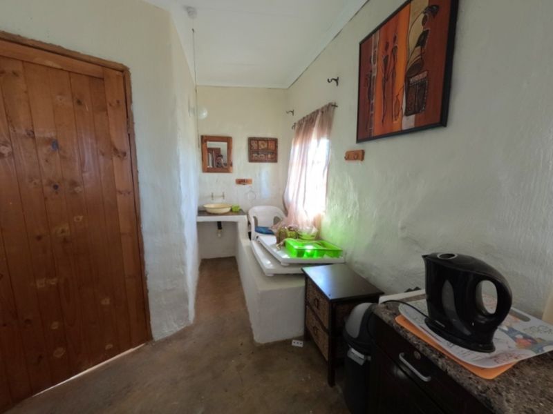A functional scullery or utility area featuring a built-in masonry counter with a basin and a solid timber door.