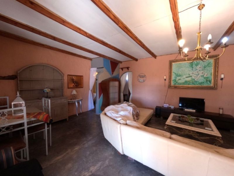 Spacious living area featuring exposed timber ceiling beams, concrete flooring, and an arched doorway, offering a rustic farm-style aesthetic.