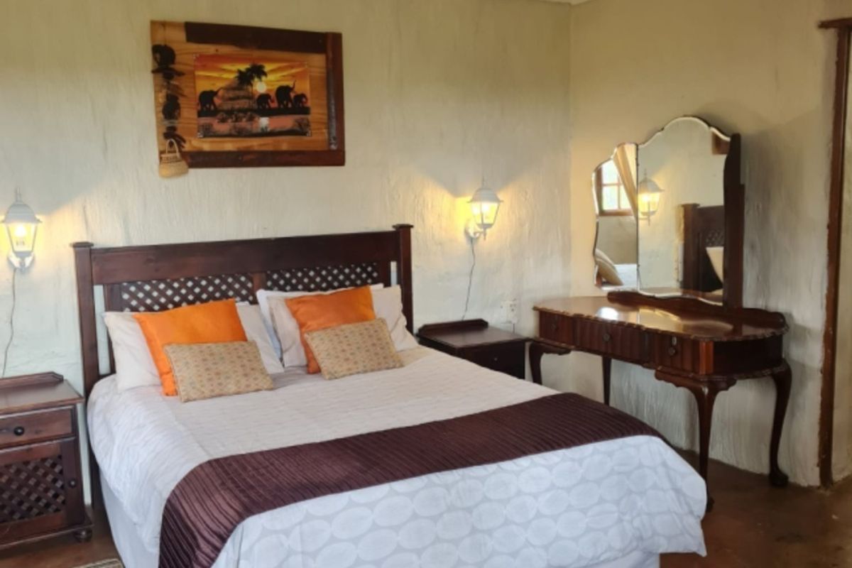 A rustic bedroom featuring textured plaster walls, concrete flooring, and wall-mounted lighting, offering a cozy and traditional farm-style aesthetic.