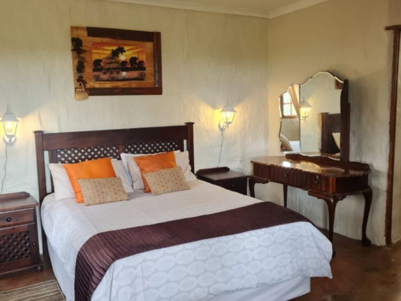 A rustic bedroom featuring textured plaster walls, concrete flooring, and wall-mounted lighting, offering a cozy and traditional farm-style aesthetic.