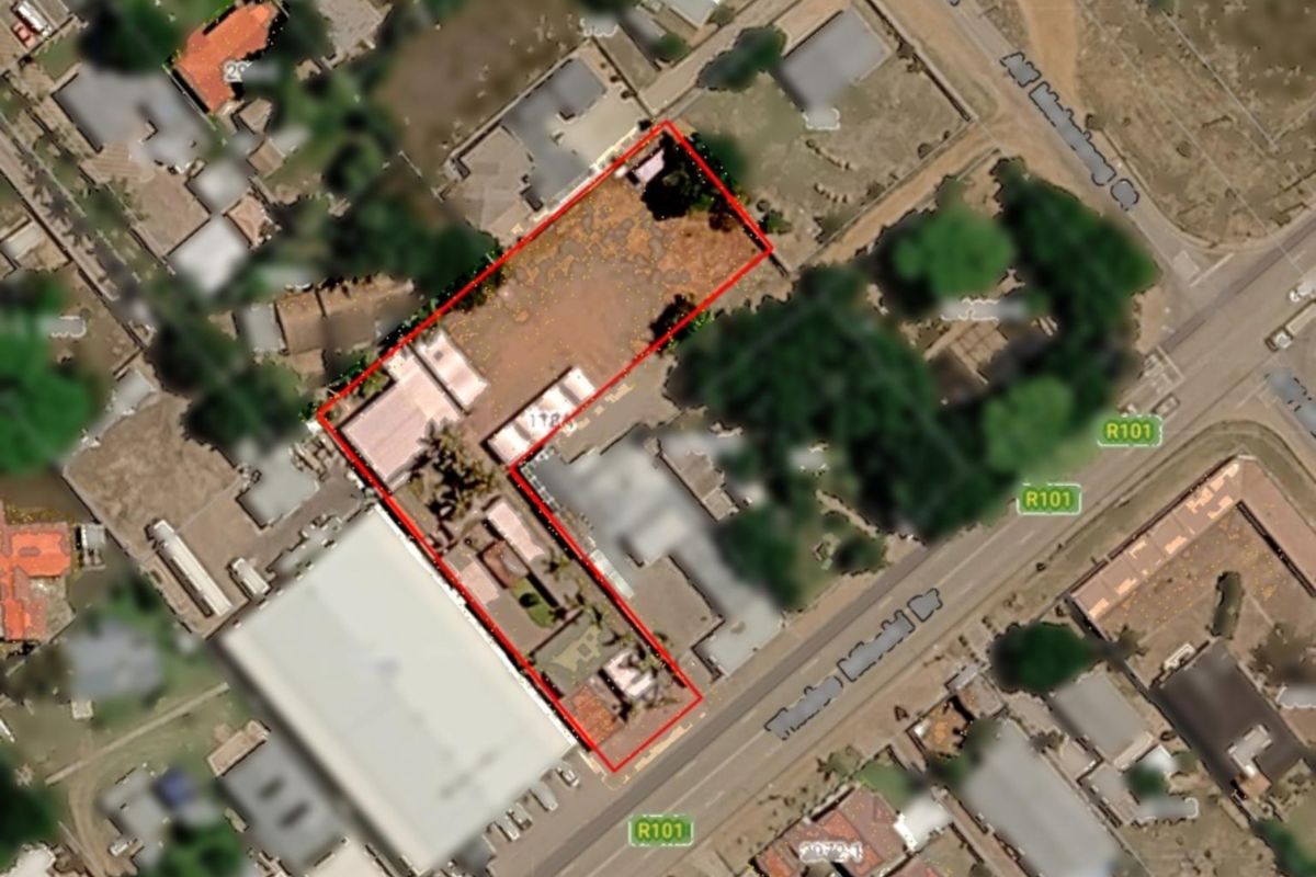 An aerial view of the commercial property site, highlighting the building layout, paved areas, and access from the main road.