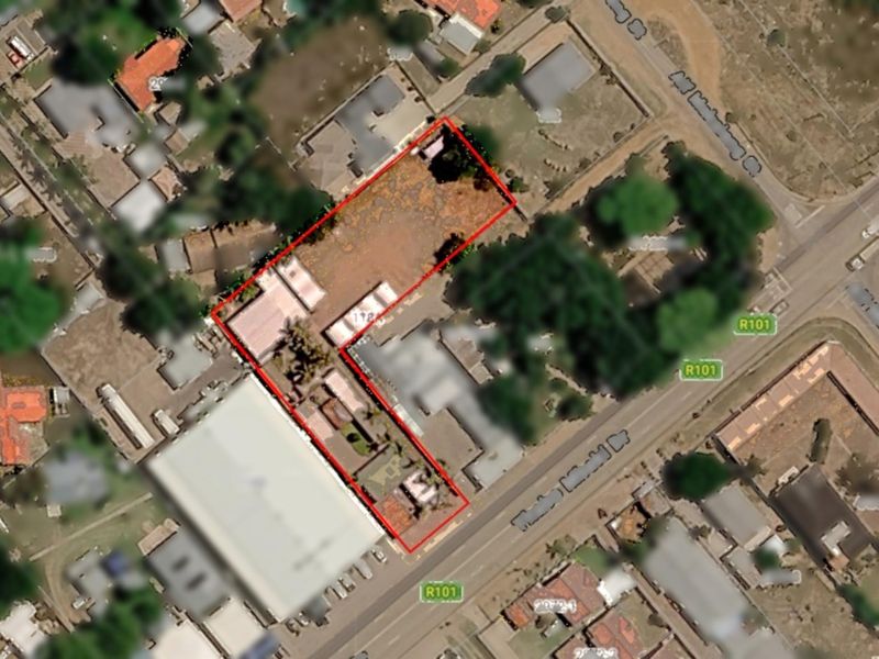 An aerial view of the commercial property site, highlighting the building layout, paved areas, and access from the main road.