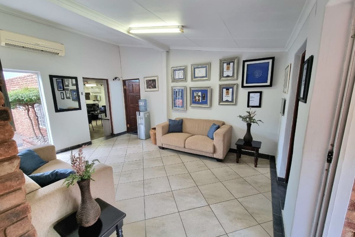 A commercial reception or waiting area featuring tiled flooring, a split-system air conditioner, and an exposed brick feature pillar.