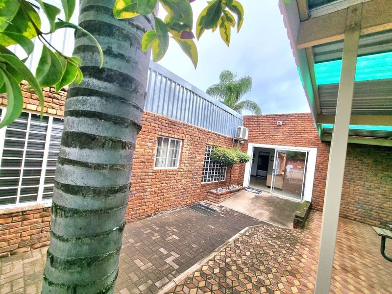 A private rear courtyard featuring exposed brick walls, paved flooring, and a sliding glass door entrance, providing a functional outdoor space for the commercial property.