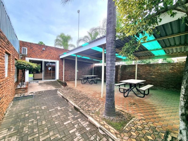 A covered outdoor patio area featuring brick walls, paved flooring, and direct access to the interior through a sliding glass door.