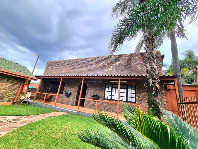 A charming face-brick commercial building featuring a covered patio, grid-pattern windows, and a well-maintained garden area with paved pathways.