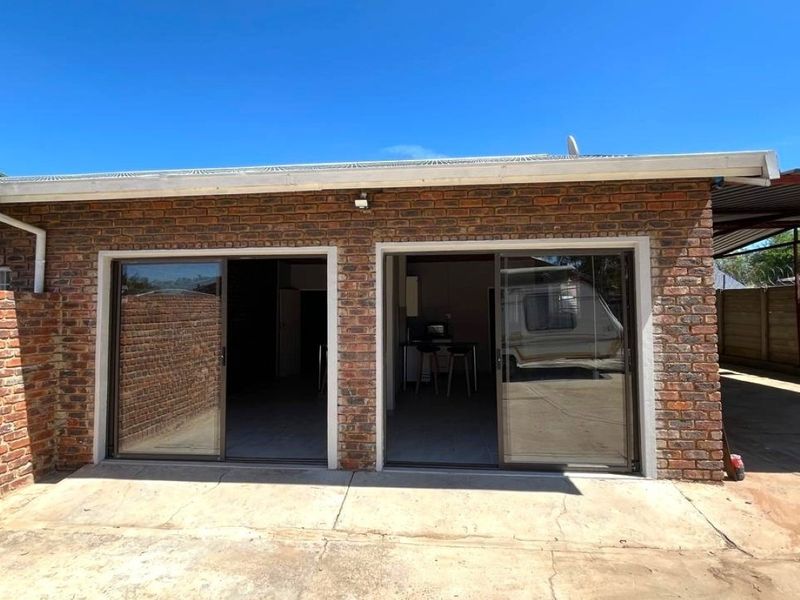 Rear exterior view of the property featuring a face brick facade, sliding glass doors, and a concrete patio area.