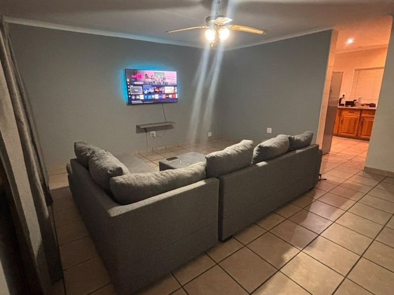 Open plan living area featuring tiled flooring, a ceiling fan, and a view into the adjacent kitchen space.
