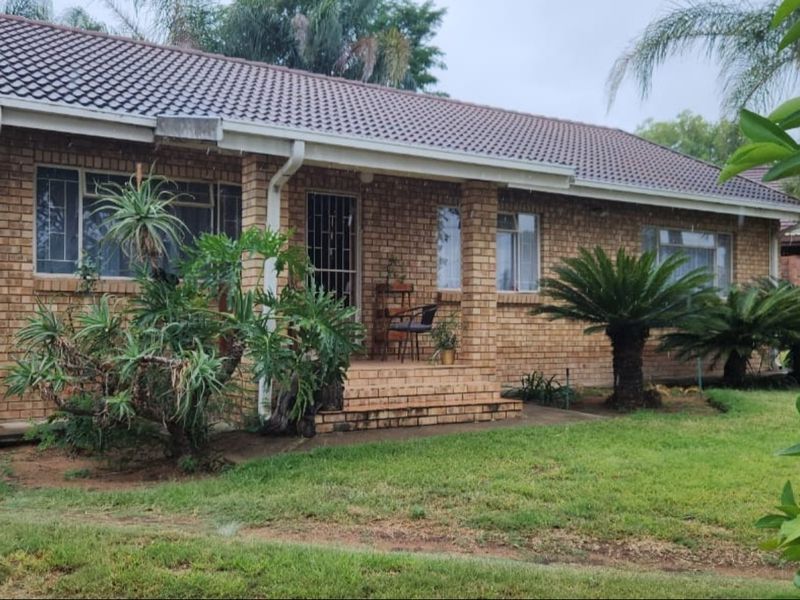 A single-story brick house featuring a tiled roof, a covered front porch, and established garden landscaping.