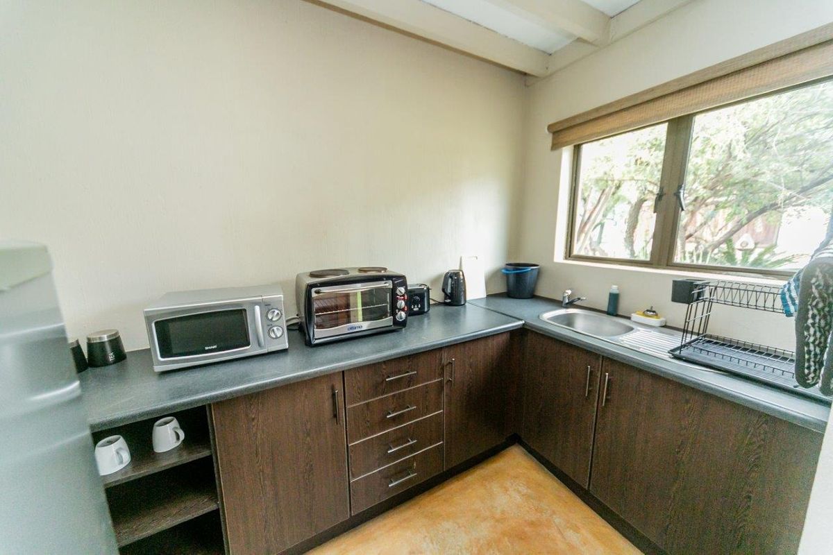 A compact kitchenette featuring dark wood-finish cabinetry, a stainless steel sink, and laminate countertops, providing essential prep space for guests.