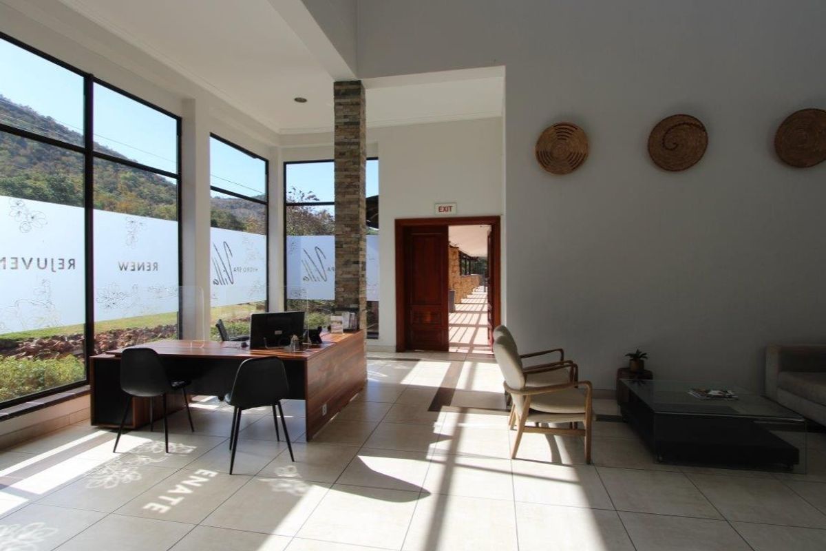 Spacious reception area featuring large floor-to-ceiling windows, a stone-clad pillar, and tiled flooring, offering a bright and welcoming atmosphere.