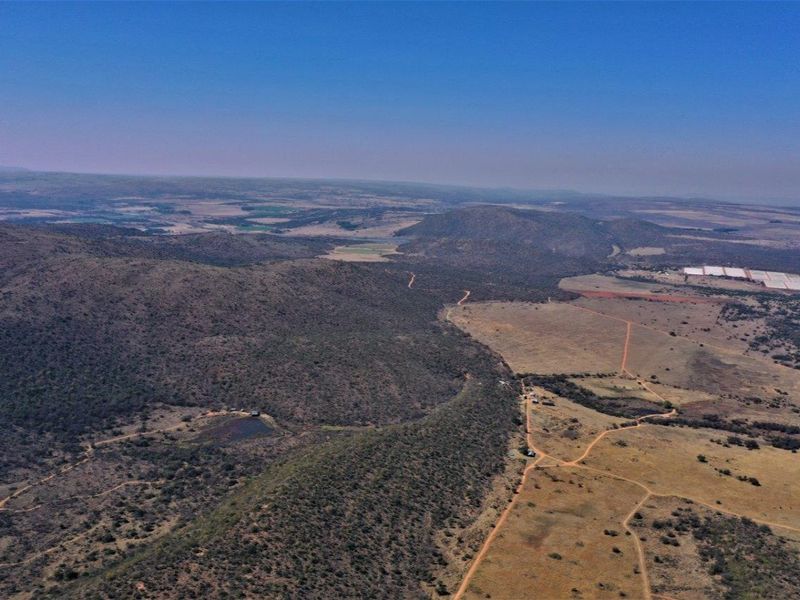 An aerial view of the expansive vacant residential land, showcasing the natural topography, surrounding hills, and existing dirt access tracks.