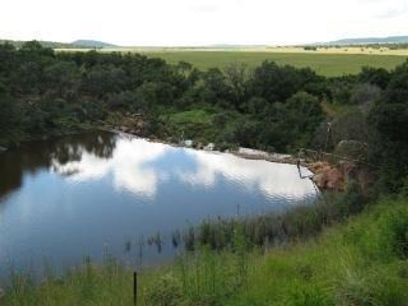 A natural dam or water feature situated on the residential land, surrounded by indigenous vegetation and open landscape views.
