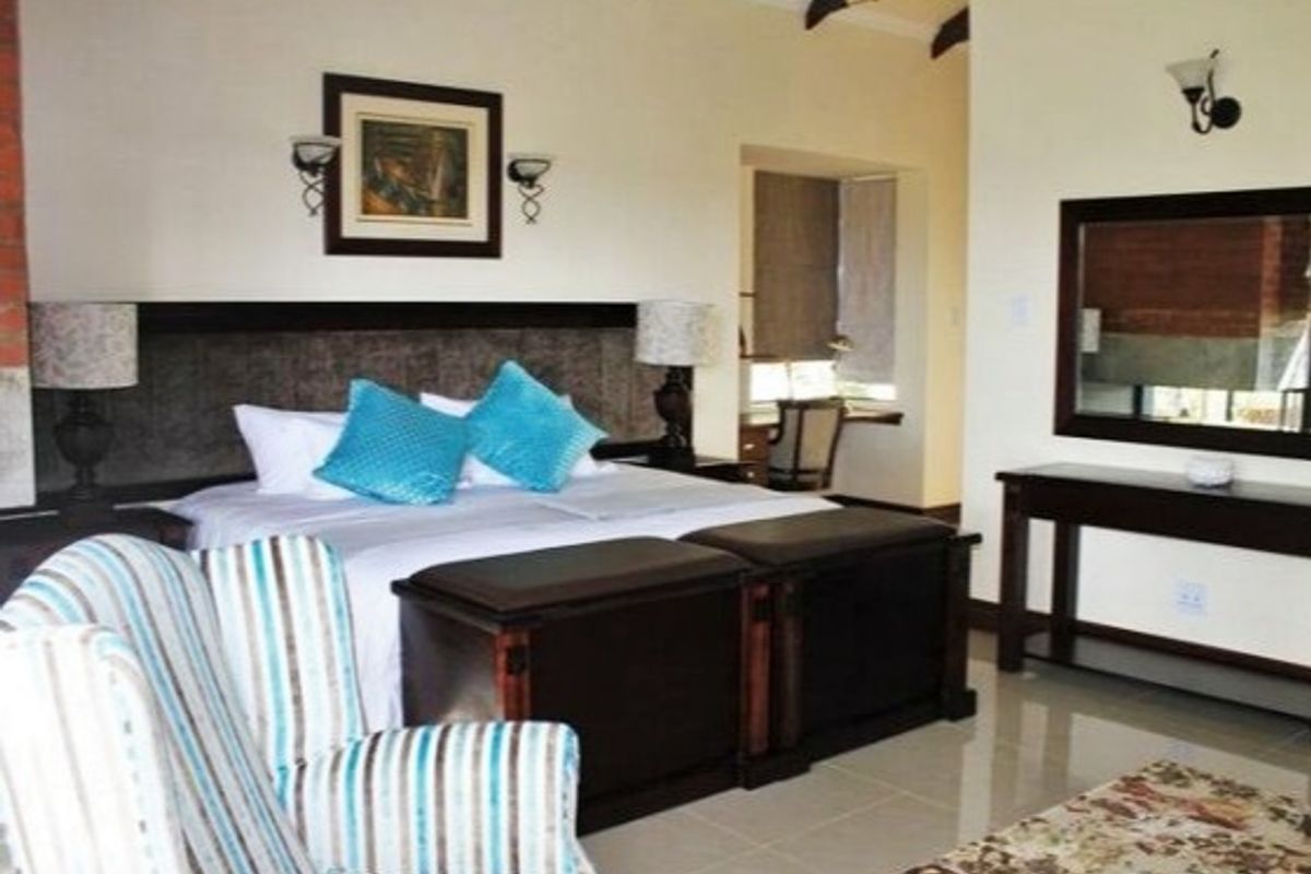 Spacious bedroom featuring high vaulted ceilings with exposed timber beams, tiled flooring, and a dedicated built-in study nook area.