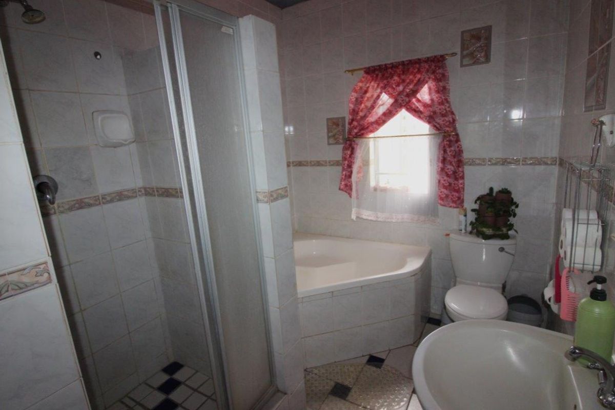 A functional bathroom featuring a corner bathtub, a separate glass-enclosed shower, a toilet, and a pedestal basin with tiled walls.