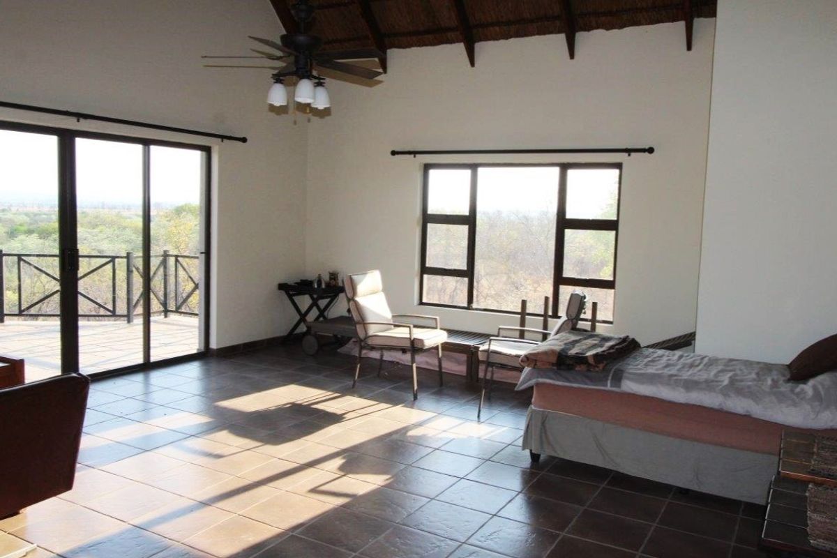 Spacious living area featuring high vaulted thatched ceilings, tiled flooring, and large sliding doors opening onto a scenic outdoor deck.